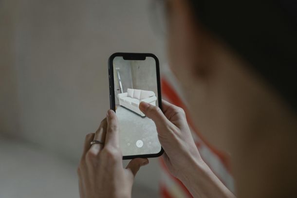 A person holds a smartphone in their hand and places a sofa projected onto the display in the room. Image source: pexels.com